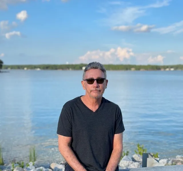 The founder of The Closet Advocate wearing glasses beside a lake.